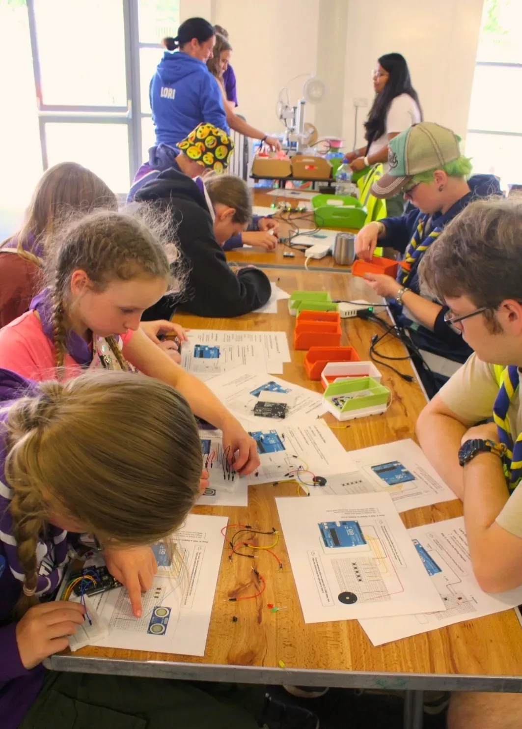 A group of young people building electronics together at a workshop.