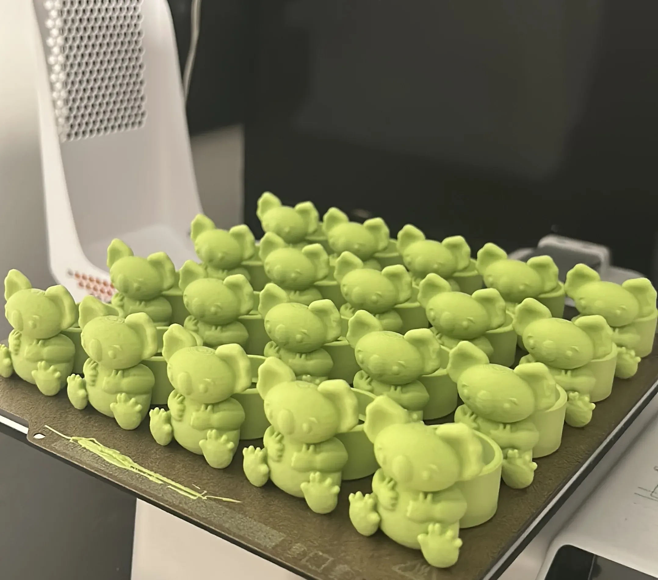 A batch of small 3D printed models fresh off the bed.